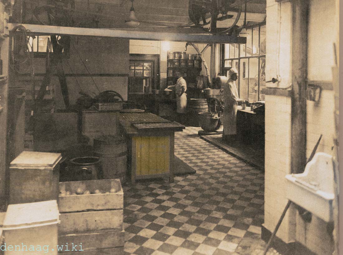 Het grondstoffenmagazijn aan de Molenstraat in 1933 met achterin het uitgaveloket. Dit was tevens de Suikerwerkerij. Hier werd bijvoorbeeld de kern van de bonbons geproduceerd. Maar de  suikerbakkers maakten ook caramels, noga's, beignets, fondant, borstplaat, suikerbeesten, bruidsuikers en hopjes.